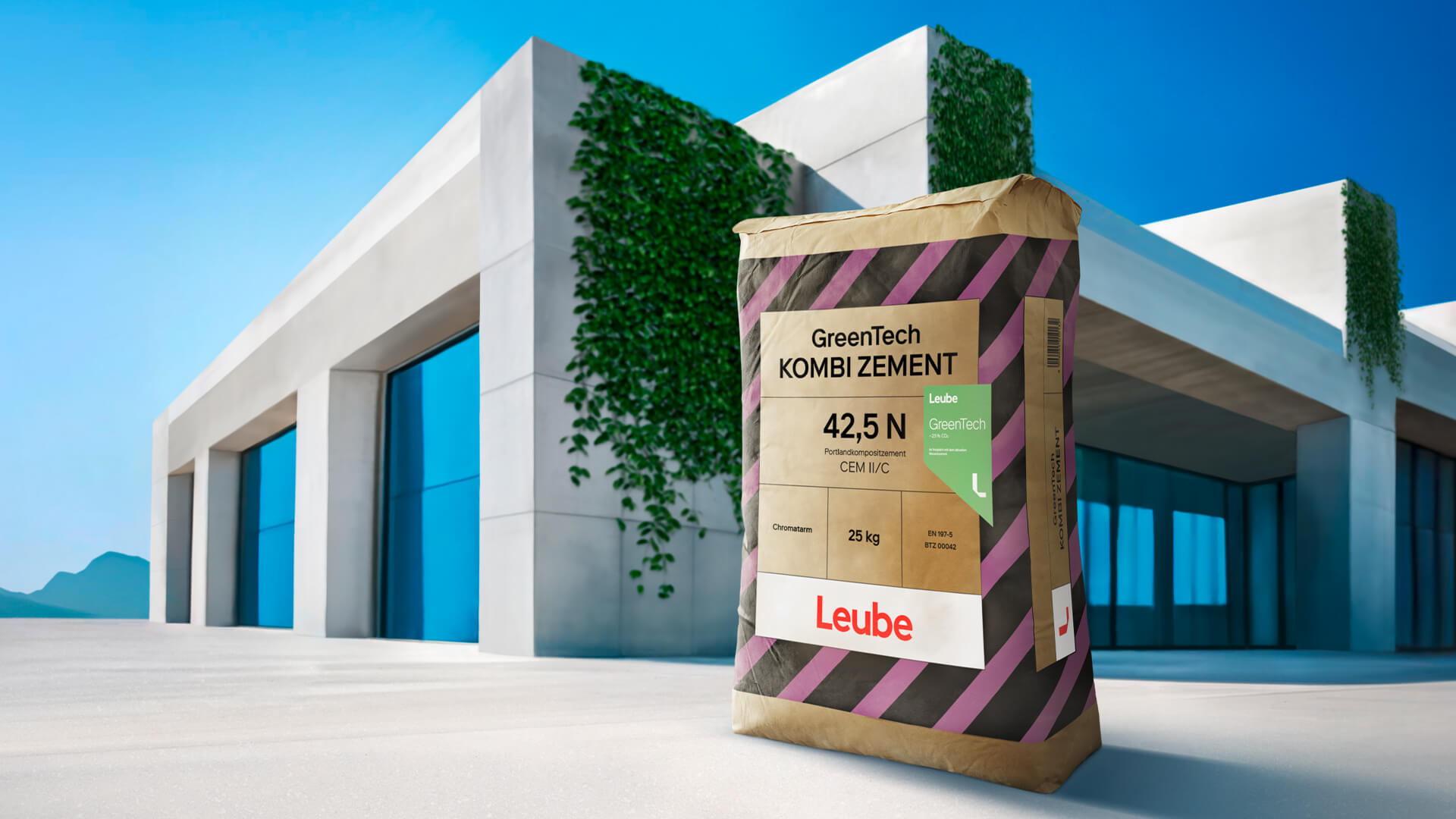 Ein Beutel Leube GreenTech Kombizement 42,5 N steht vor einem modernen Gebäude mit begrünten Wänden. Der Beutel ist braun mit gelb-schwarzen Streifen und zeigt das Produktetikett. Das Gebäude hat große Fenster und eine helle Fassade.