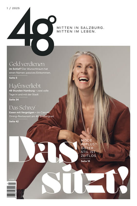 Das Bild zeigt eine lächelnde Frau mit einem Glas Rotwein in der Hand, umgeben von Weinflaschen und einem Buch mit dem Titel "Das süße Gift". Im Hintergrund sind Berge zu erkennen.