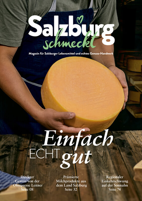 Ein Koch hält ein frisch gebackenes Salzburger Nockerl in den Händen, präsentiert auf einem Buchcover mit dem Titel "Salzburg schmeckt einfach ECHT gut".