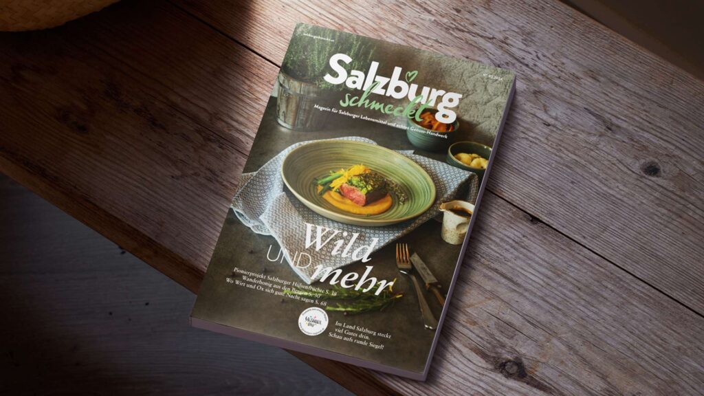 Eine Flasche Salzburger Wildnis Bier steht auf einem Holztisch. Das Etikett zeigt einen Hirsch und den Schriftzug "Salzburger Wildnis".